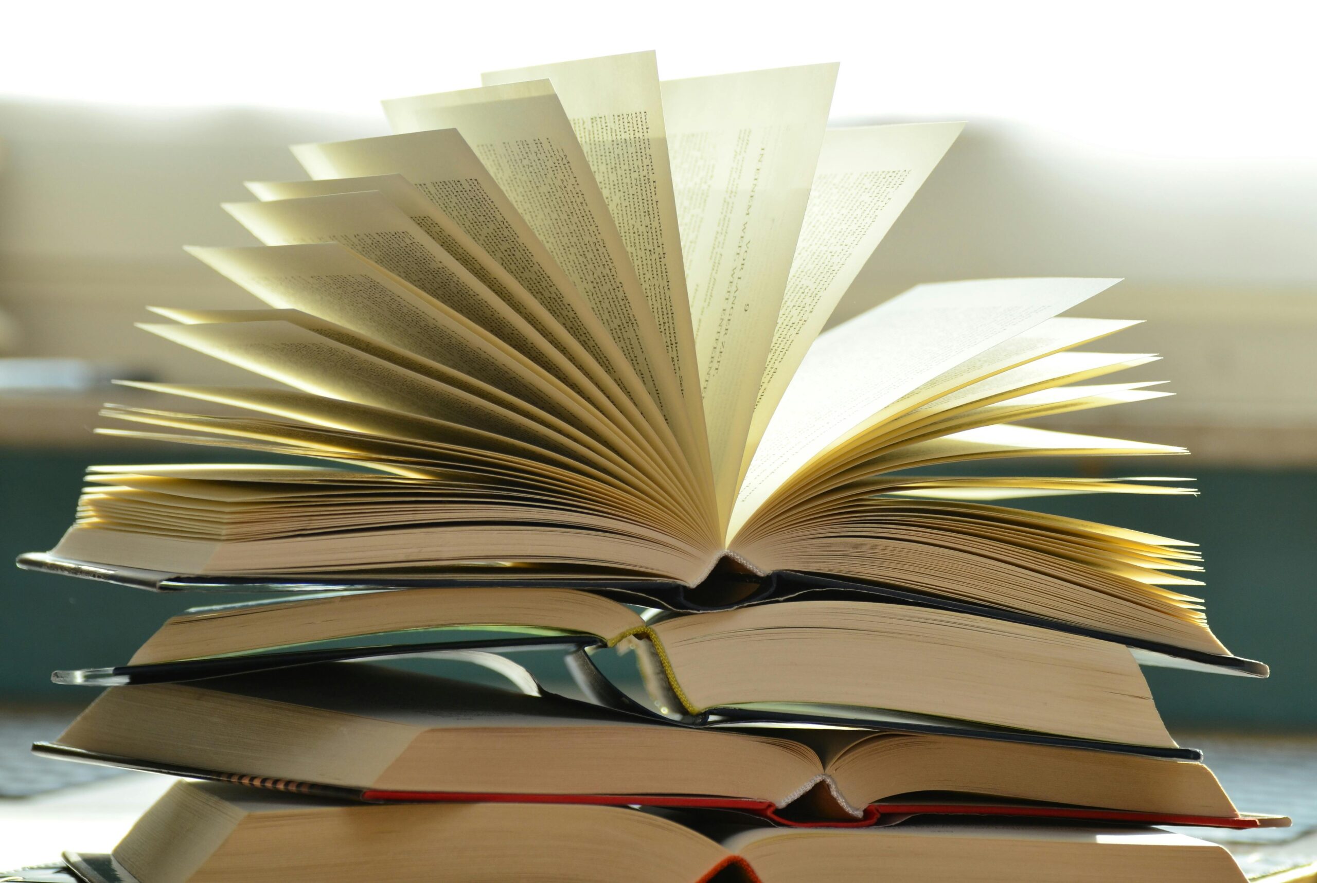 Open book with fanned pages on top of stacked books.